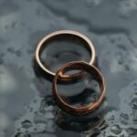 Wedding rings left on a rain slicked surface_u