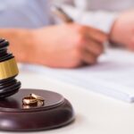 gavel with wedding rings and someone writing in the background_s