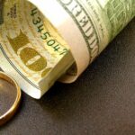 wedding ring lies next to 100 dollar bill