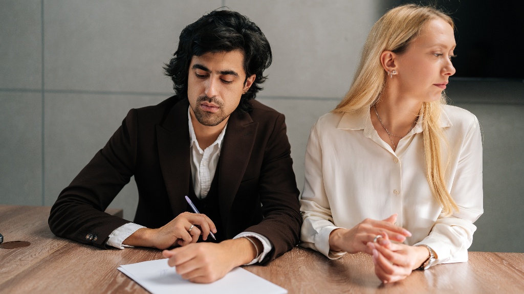 man is signing divorce documents with wife