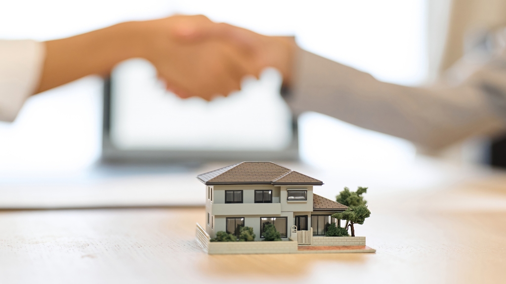 man and a woman shaking hands and house model