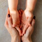 woman holds a child’s hands in her hands_s