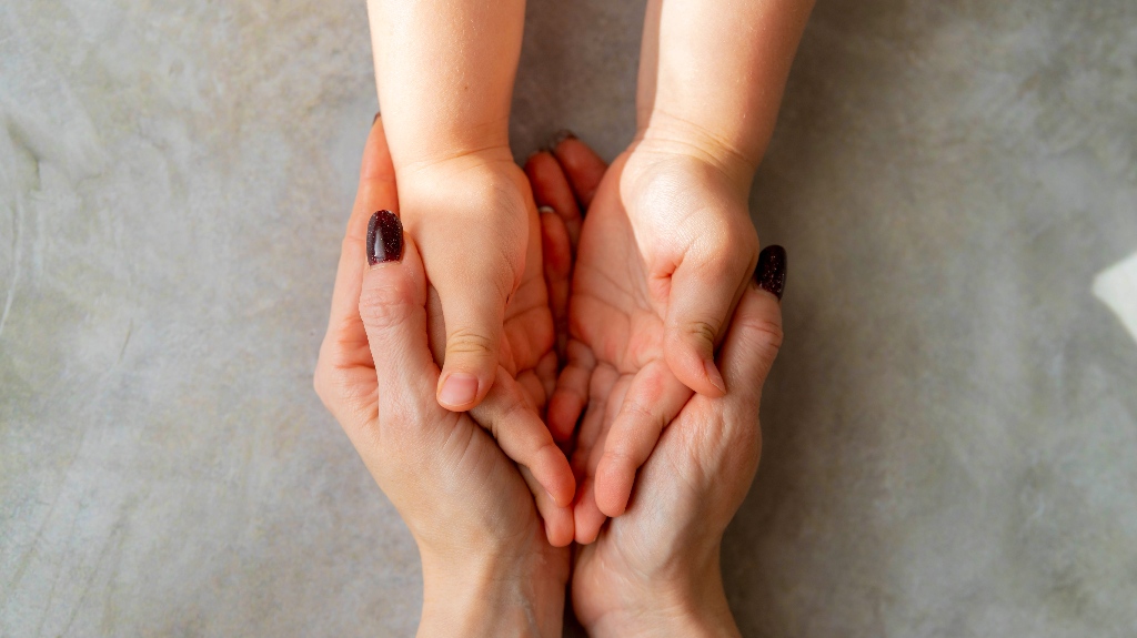 woman holds a child's hands in her hands