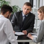 Unhappy young couple visiting divorce lawyer in office_s