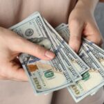 Woman with dollar banknotes on grey background_s