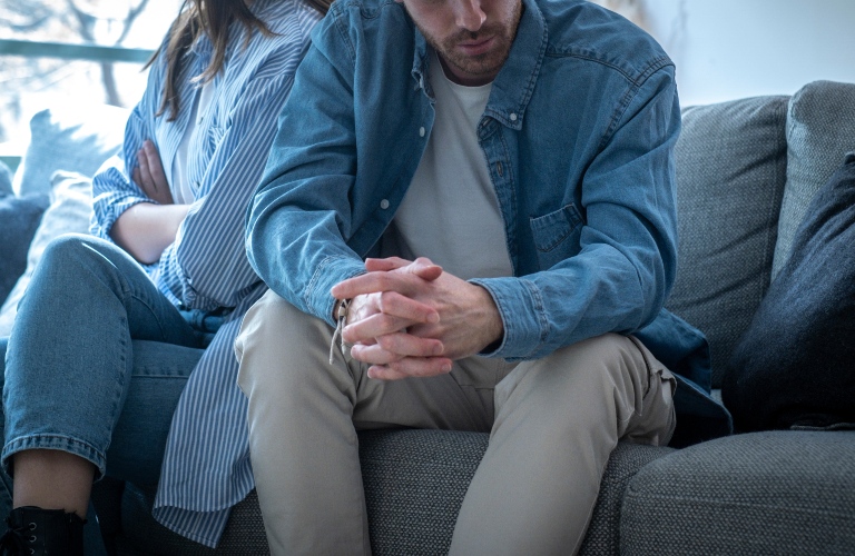 cut out of unhappy young couple sitting apart have relationship problems