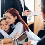 A mother comforts her young daughter during a meeting with a lawyer in an office_ss